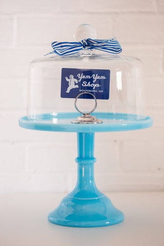 A Yum Yum Shop gift card placed inside a blue and glass cake stand.